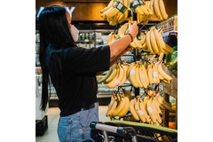 Image Woman grocery shopping for bananas.